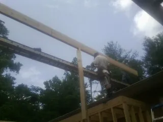 Carpenter setting a ridge beam over a new addition frame — Ice Dam Removal by Roofing Brothers in Tipton