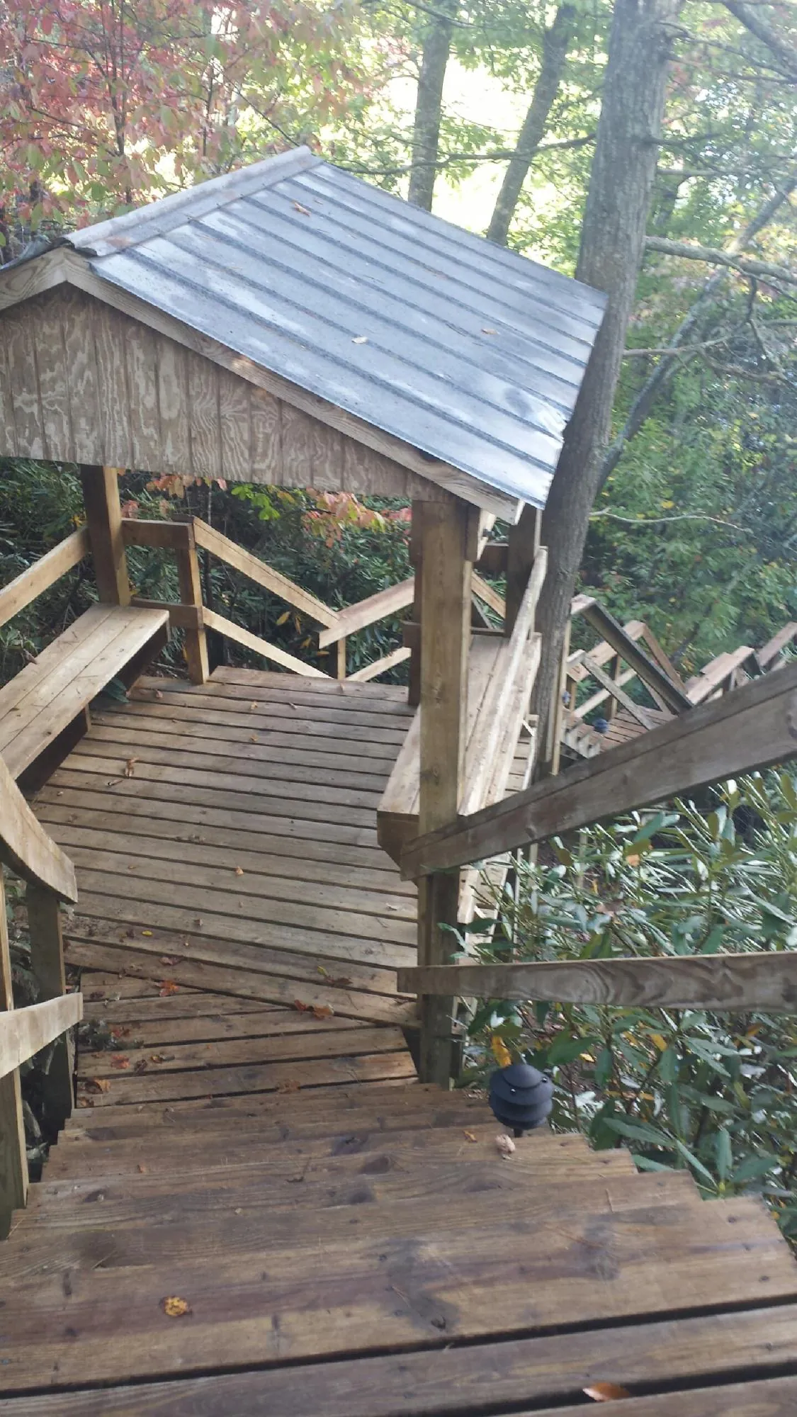 Metal roofed shelter over wooden steps on a wooded walkway — Skylight Repair & Installation work by our crew in Tipton